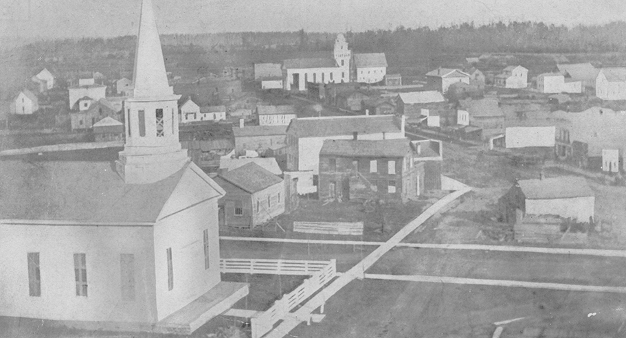 Black and white photo of Lapeer in 1854, showing church house and other buildings