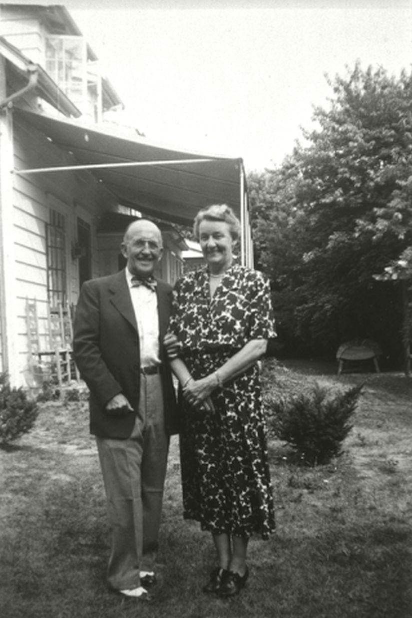 Man holding a women's arm in front of the porch of a house.