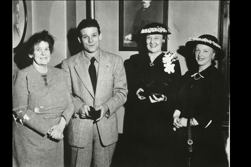 A man and three women posing for a photo, the man and one of the women is holding a black award case.