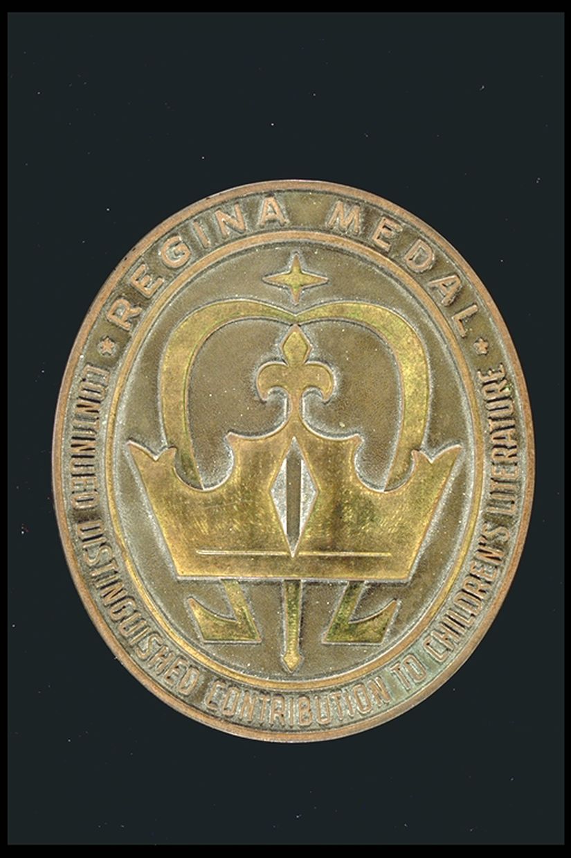 Oval gold medal with an image of a crown with the words: Regina Medal. Continued Distinguished contribution to children's literature" around the outside of the medal.
